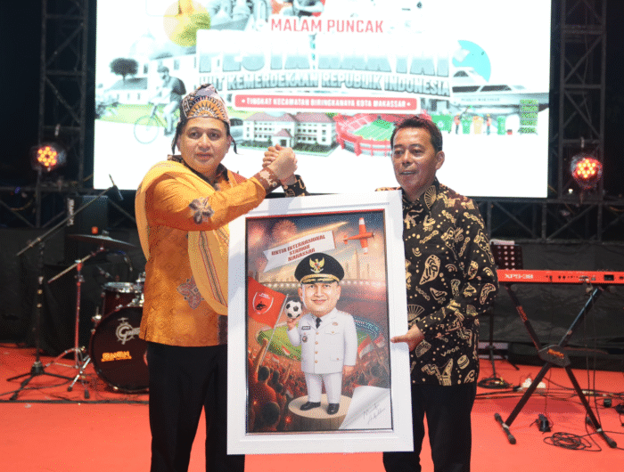 Sumber Foto : Humas Pemkot, Wali Kota Makassar, Munafri Arifuddin, menerima karikatur bertema Stadion Internasional Untia saat malam puncak pesta rakyat Kecamatan Biringkanaya, Selasa (26/8/2025) malam.