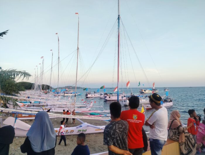 Humas Pemprov, Sejumlah perahu Sandeq berjejer di bibir Pantai Bahari Polewali menjelang pelaksanaan etape pertama Sandeq Silumba 2025, Rabu (20/8/2025). Tampak warga antusias menyaksikan persiapan lomba perahu tradisional kebanggaan masyarakat Mandar tersebut.