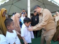 Wali Kota Makassar Munafri Arifuddin memakaikan seragam baru kepada salah satu siswa penerima program seragam gratis di Makassar, Jumat (22/8/2025).