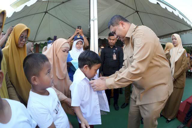 Wali Kota Makassar Munafri Arifuddin memakaikan seragam baru kepada salah satu siswa penerima program seragam gratis di Makassar, Jumat (22/8/2025).