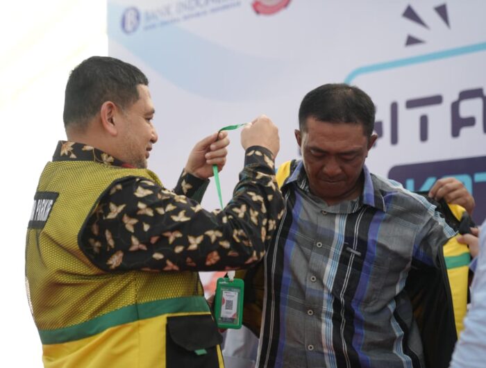 Sumber Foto : Humas Pemkot, Wali Kota Makassar Munafri Arifuddin mengenakan rompi dan memasangkan kalung identitas QRIS kepada perwakilan juru parkir saat peluncuran program Digitalisasi Parkir di Jl. WR Supratman, Makassar, Senin (1/9/2025).