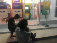 Sumber Foto : Tim Redaksi, Dua nasabah duduk menunggu di depan gerai ATM Bank Syariah Indonesia (BSI) dan BRI di Gowa saat terjadi gangguan penarikan tunai, Rabu (3/9/2025) malam.