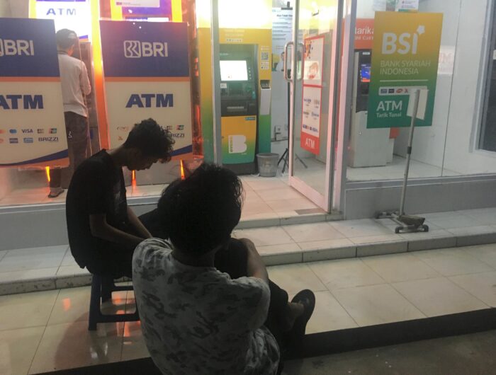 Sumber Foto : Tim Redaksi, Dua nasabah duduk menunggu di depan gerai ATM Bank Syariah Indonesia (BSI) dan BRI di Gowa saat terjadi gangguan penarikan tunai, Rabu (3/9/2025) malam.